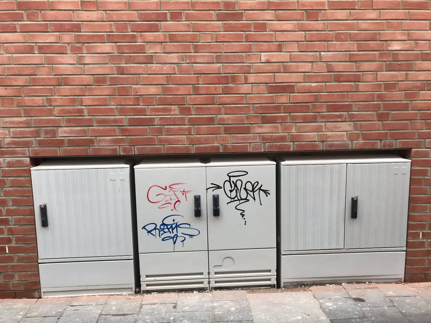 Stromkästen und Klinkerfassade mit Graffiti-Tags vor der Behandlung